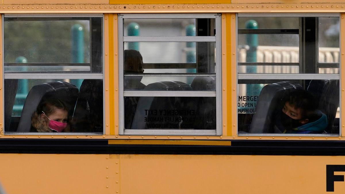 Elementary school students sit on board a school bus after attending in-person classes at...