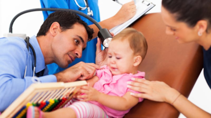 pediatric doctor examining a sick baby's ear