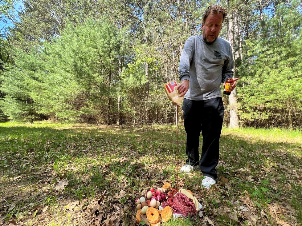 Alex Williams pours a bottle of maple syrup on a pile of doughnuts, pies, and other sweet...